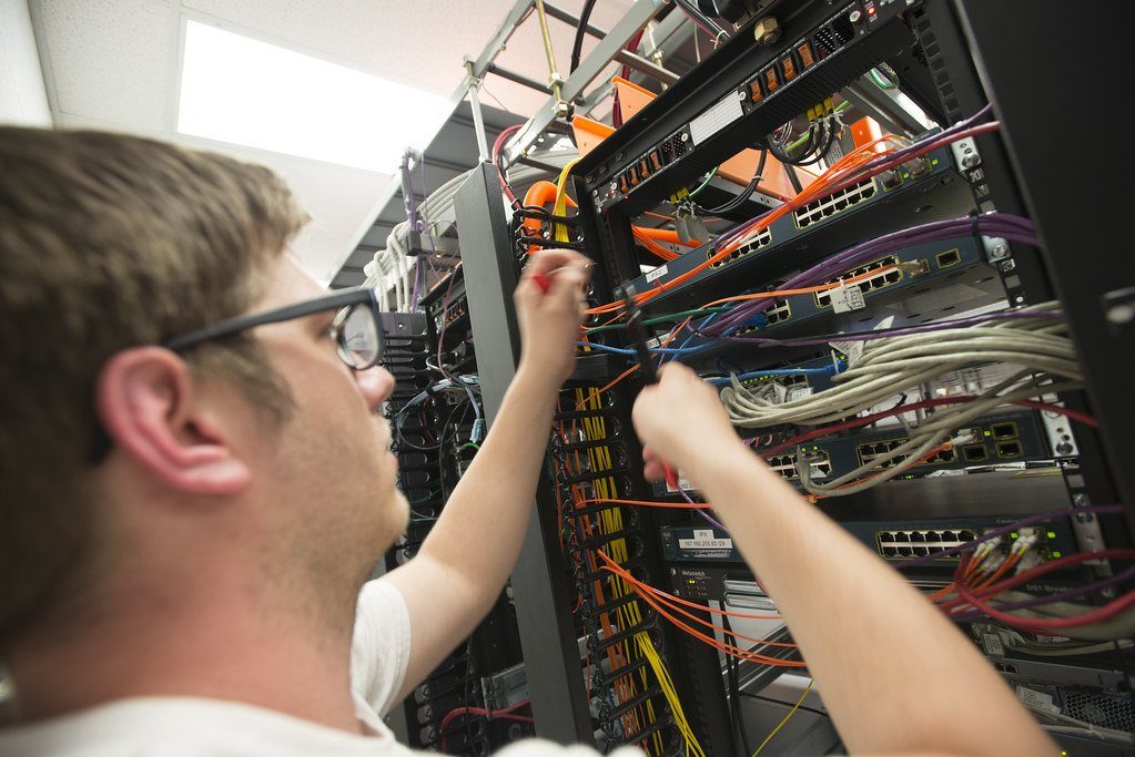 An engineer patching cables in a network rack